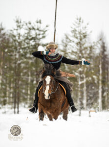 Person riding horse and shoot with bow in snowy landscape